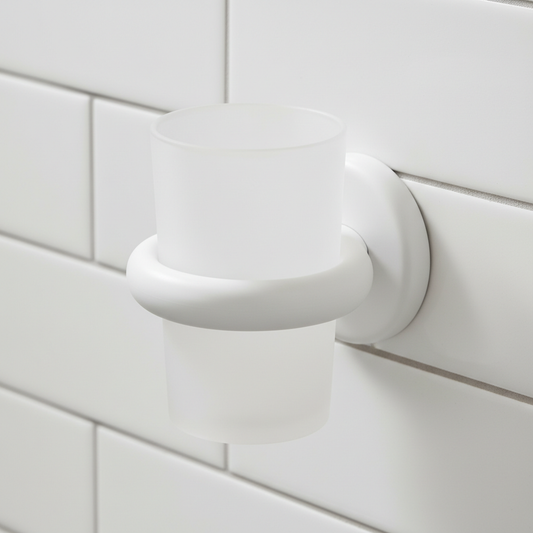 Matte white wall-mounted toothbrush cup holder on white tile wall